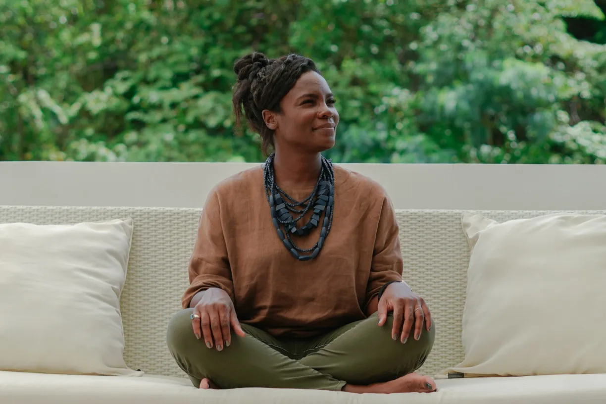 Kali Fields Williams sitting relaxed on a white couch surrounded by greenery